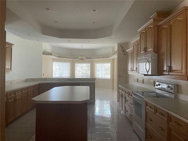 kitchen featuring tile patterned floors, a center island, a raised ceiling, white appliances, and backsplash