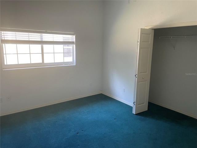 unfurnished bedroom featuring dark carpet and a closet