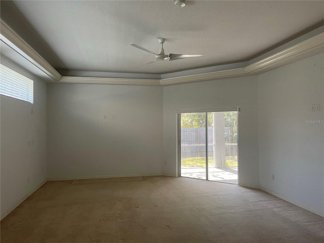 unfurnished room with ceiling fan, a tray ceiling, light carpet, and a textured ceiling