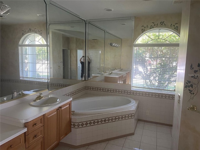 bathroom featuring vanity, tiled bath, tile patterned flooring, and a wealth of natural light