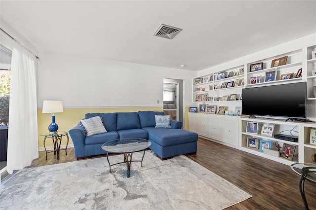 living room with built in shelves and wood-type flooring