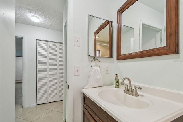 bathroom with tile patterned flooring, vanity, and a textured ceiling