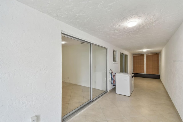 hallway featuring a textured ceiling and light tile patterned floors