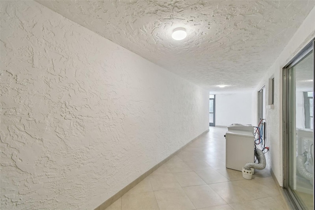 corridor featuring light tile patterned floors and a textured ceiling