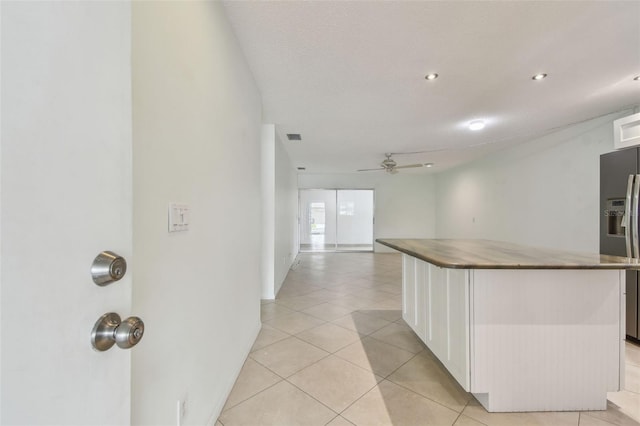 kitchen with light tile patterned floors, stainless steel refrigerator with ice dispenser, a textured ceiling, ceiling fan, and white cabinets