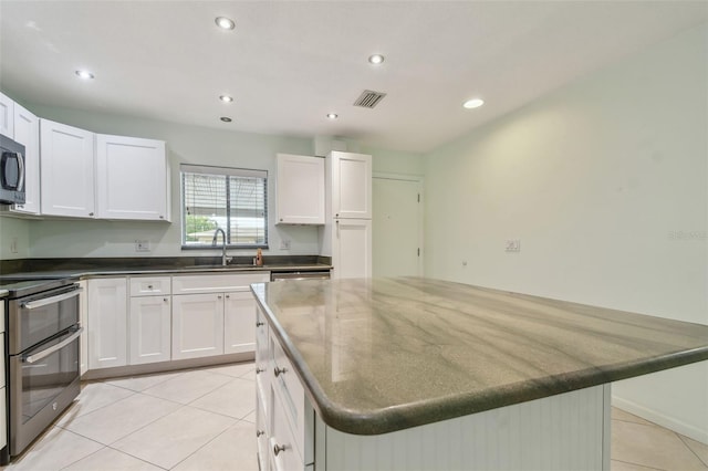 kitchen with appliances with stainless steel finishes, white cabinets, and a center island