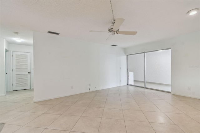 tiled empty room with ceiling fan and a textured ceiling