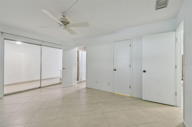 unfurnished bedroom with ensuite bathroom, light tile patterned floors, and ceiling fan