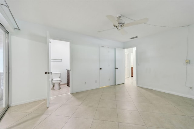 unfurnished bedroom featuring connected bathroom, light tile patterned flooring, and ceiling fan