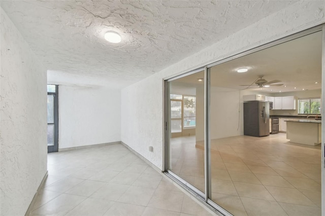 corridor featuring a textured ceiling, sink, and light tile patterned flooring