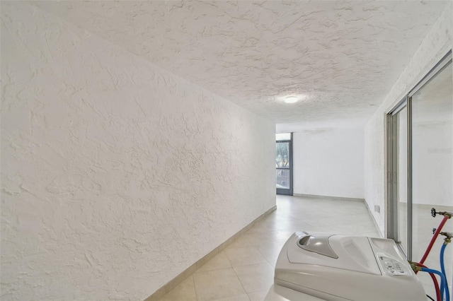 hall with light tile patterned floors, washer / clothes dryer, and a textured ceiling