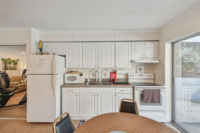 kitchen with white appliances, a textured ceiling, white cabinets, light tile patterned floors, and sink