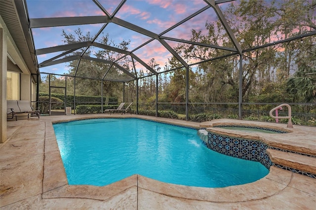 pool at dusk featuring glass enclosure, an outdoor pool, a patio, and an in ground hot tub