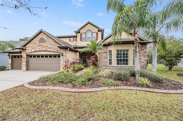 traditional-style house featuring stucco siding, fence, a garage, stone siding, and driveway