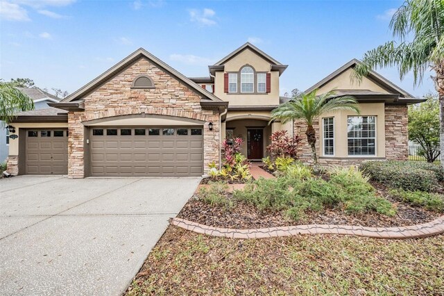 traditional-style house featuring an attached garage, stone siding, concrete driveway, and stucco siding