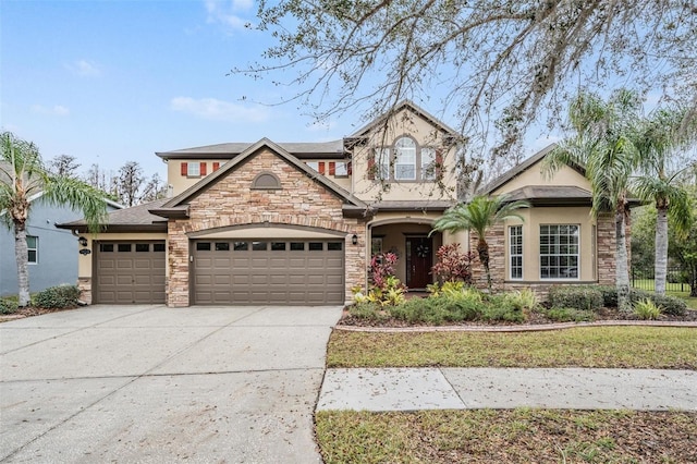 view of front of home with stone siding, concrete driveway, an attached garage, and stucco siding