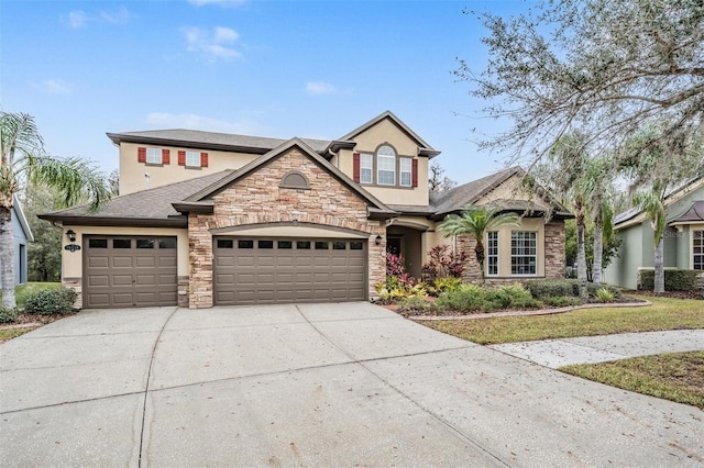 traditional-style home featuring driveway, stone siding, an attached garage, and stucco siding