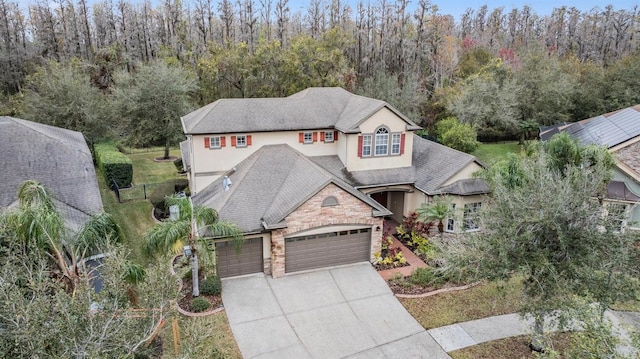 view of front of home featuring a garage, concrete driveway, stone siding, fence, and stucco siding