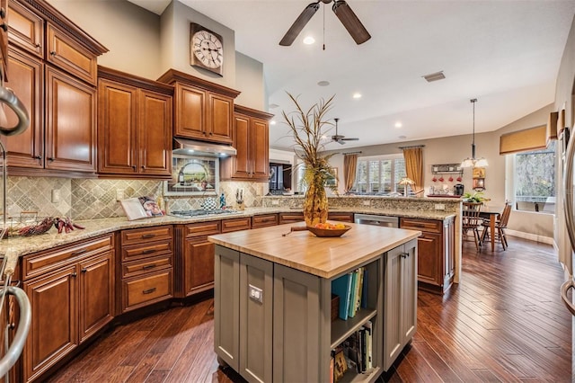 kitchen featuring visible vents, a peninsula, stainless steel appliances, under cabinet range hood, and wooden counters