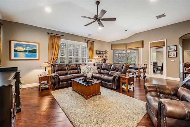 living room featuring dark wood-style floors, vaulted ceiling, arched walkways, and visible vents