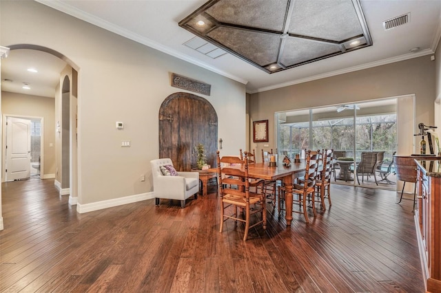 dining room with arched walkways, visible vents, baseboards, ornamental molding, and hardwood / wood-style floors