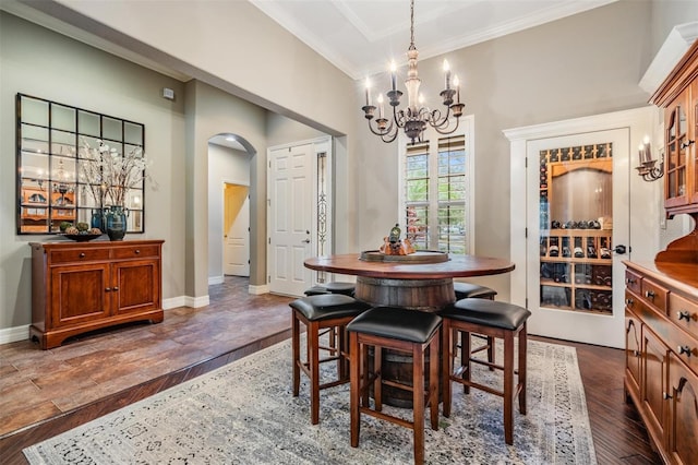 dining space featuring crown molding, arched walkways, dark wood finished floors, and baseboards