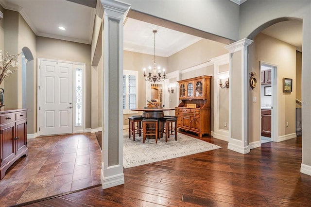 foyer with dark wood-style floors, arched walkways, crown molding, and ornate columns