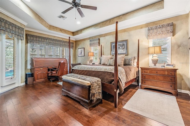 bedroom featuring crown molding, a raised ceiling, visible vents, dark wood-type flooring, and baseboards