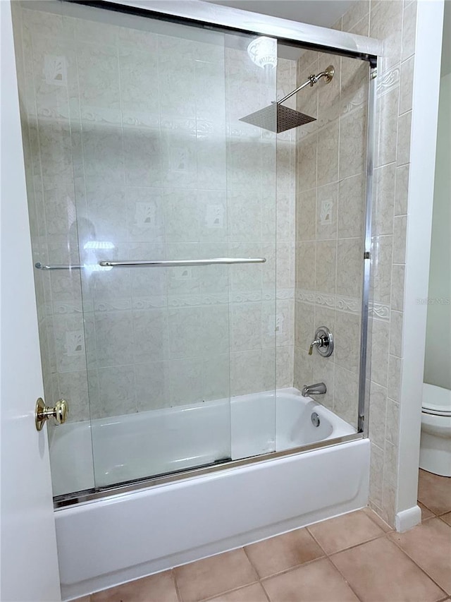 bathroom with combined bath / shower with glass door, tile patterned floors, and toilet