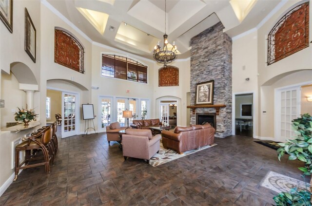 living room featuring an inviting chandelier, a stone fireplace, and ornamental molding