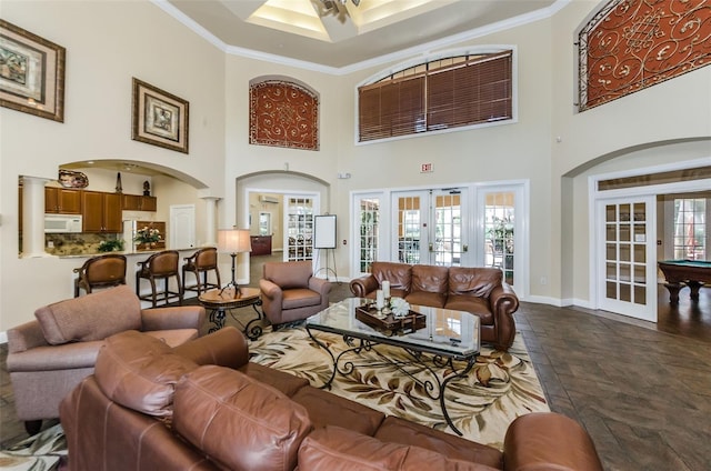 living room with decorative columns, ornamental molding, a towering ceiling, and french doors