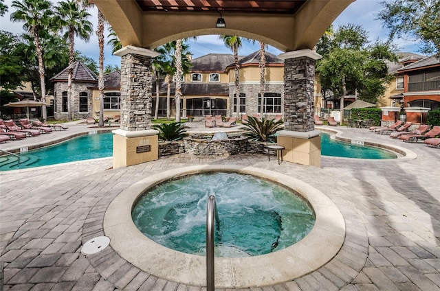 view of swimming pool featuring a hot tub and a patio