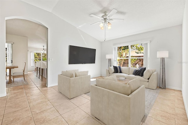 tiled living room with lofted ceiling, a textured ceiling, and ceiling fan