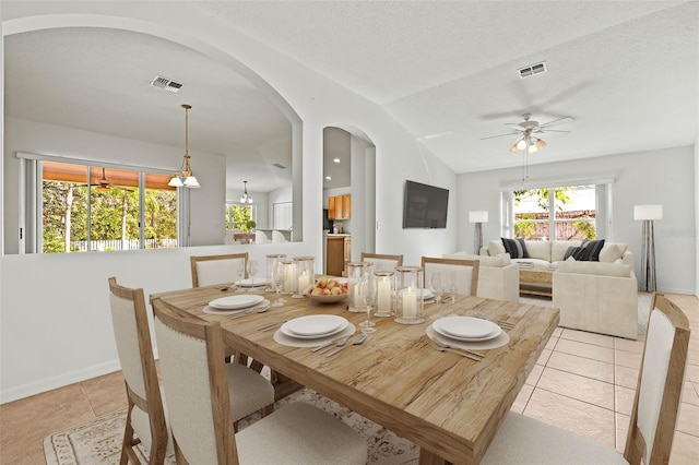 dining room featuring light tile patterned flooring, ceiling fan, lofted ceiling, and a textured ceiling