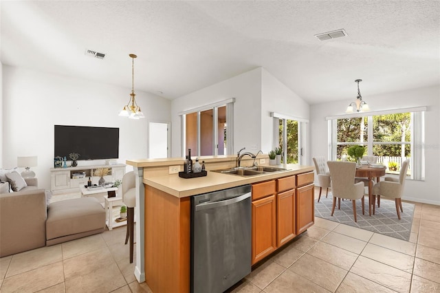 kitchen with a center island with sink, sink, stainless steel dishwasher, and decorative light fixtures