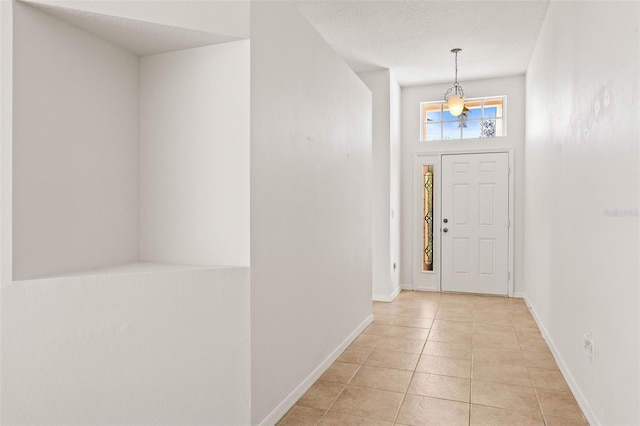 entrance foyer with baseboards, a textured ceiling, and light tile patterned flooring