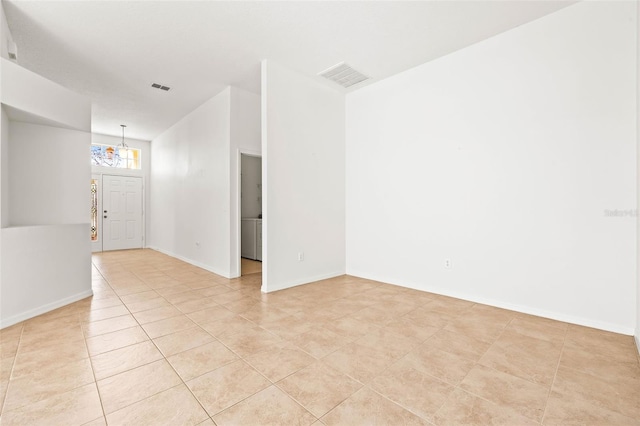 empty room featuring light tile patterned flooring and a chandelier