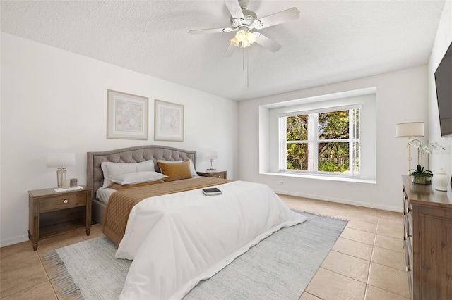 bedroom featuring light tile patterned floors, baseboards, and a textured ceiling