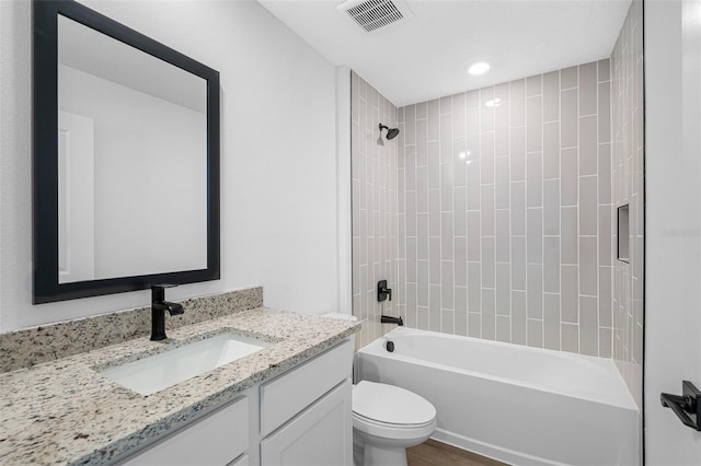 full bathroom with hardwood / wood-style flooring, vanity, toilet, and tiled shower / bath combo