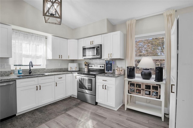 kitchen featuring decorative backsplash, appliances with stainless steel finishes, stone countertops, and a sink