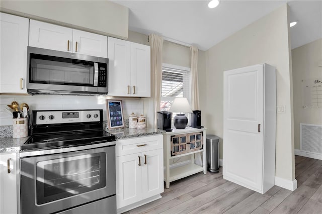 kitchen featuring light wood-type flooring, visible vents, backsplash, appliances with stainless steel finishes, and light stone countertops