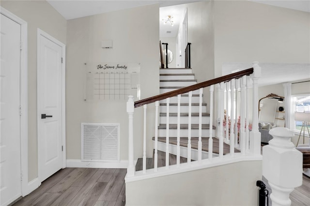 staircase featuring wood finished floors, visible vents, and baseboards