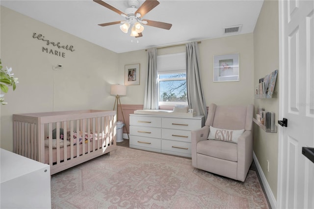 bedroom featuring visible vents, a ceiling fan, and a nursery area