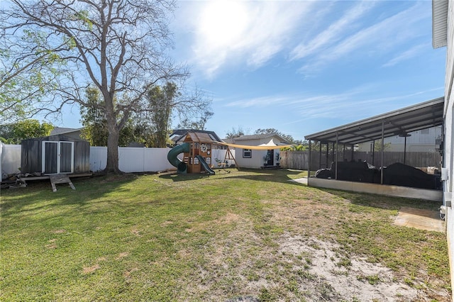 view of yard with an outbuilding, a fenced backyard, a playground, a storage shed, and a sunroom