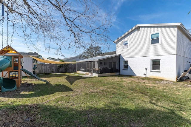 rear view of house with a playground, fence, stucco siding, a yard, and a sunroom