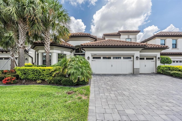 mediterranean / spanish house featuring a garage and a front yard