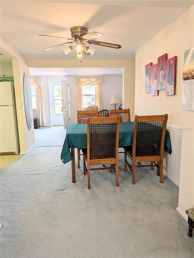 dining space with ceiling fan and light carpet