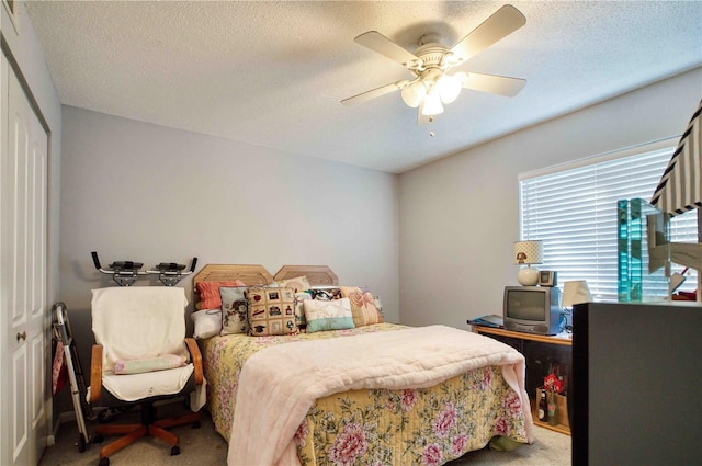 carpeted bedroom featuring ceiling fan, a closet, and a textured ceiling