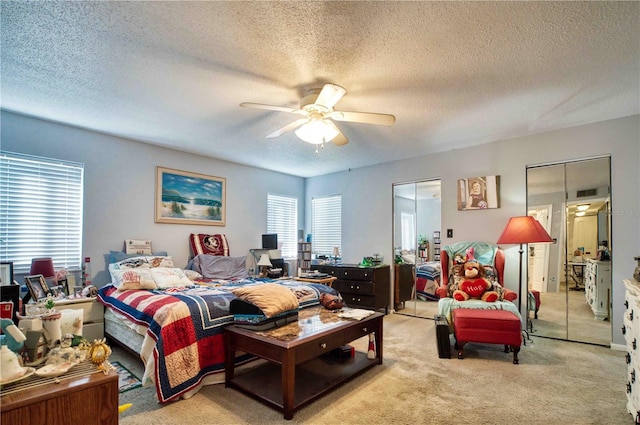 bedroom featuring a textured ceiling, light colored carpet, and ceiling fan