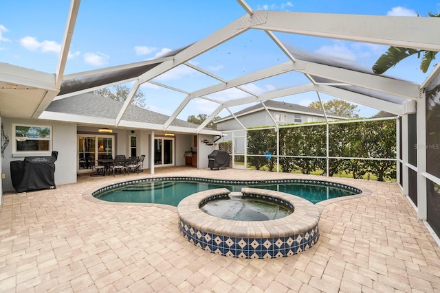 view of pool featuring an in ground hot tub, area for grilling, glass enclosure, and a patio area